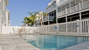 A swimming pool with a white fence, lounge chairs, and palm trees. - Ocean View 6 Bedroom 4 Bath Home Cooled/Heated Pool No Typical Hidden Fees!! (Tybee Island)
