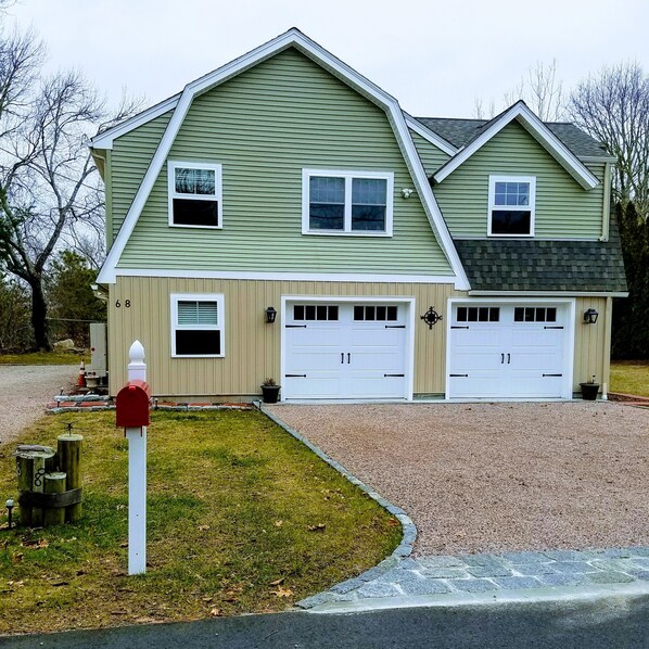 A two-story house with a green siding exterior, two garage doors, and a red mailbox.