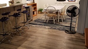 A kitchen with wooden cabinets, a bar area with stools, a dining table with chairs, a fan, and a ceiling fan. - Beautifully Renovated, Central AC, wash/dryer, dishwasher, New Appliances. (Charlestown)