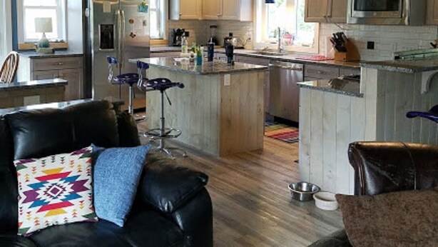 A modern kitchen with wooden cabinets, a central island, and a dining area with leather chairs. - Beautifully Renovated, Central AC, wash/dryer, dishwasher, New Appliances. (Charlestown)