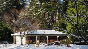 Una casa de dos pisos con fachada de ladrillo, un porche cubierto y un tejado cubierto de nieve.