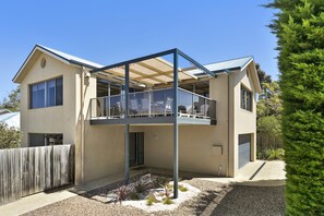 Ein zweistöckiges Haus mit Balkon, Holzzaun und kleinem Garten.