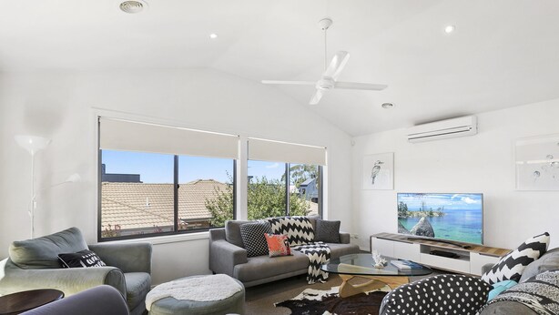 A modern living room with a large TV, grey sofas, a glass coffee table, and a ceiling fan. - Torquay Sea-Cret (Torquay)