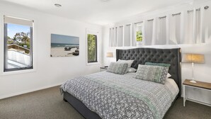 A bedroom with a large bed, a window with a view of the beach, and a ceiling light. - Torquay Sea-Cret (Torquay)