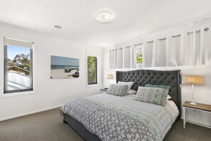 Ein Schlafzimmer mit einem großen Bett, einem Fenster mit Blick auf den Strand und einer Deckenleuchte.