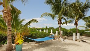 A hammock between palm trees on a sandy beach with a clear sky. - 5BR luxury home w/ pool, theater, rooftop deck & 100-ft dock near beach! (Marathon)
