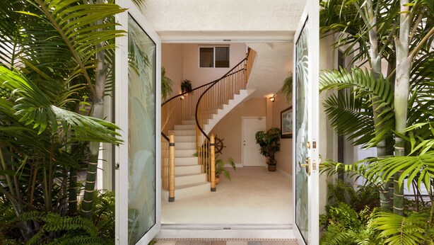 A staircase leading to a second floor, surrounded by lush tropical plants. - 5BR luxury home w/ pool, theater, rooftop deck & 100-ft dock near beach! (Marathon)