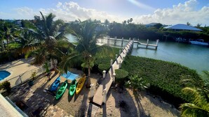 A waterfront property with a wooden dock, a pool, and several kayaks. - 5BR luxury home w/ pool, theater, rooftop deck & 100-ft dock near beach! (Marathon)