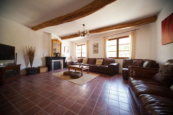 A spacious living room with a fireplace, leather sofas, and a television.