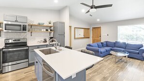 A modern kitchen with a central island, built-in appliances, and a dining area with a blue sofa and glass table. - Comfortable #Staycay Close to Everything In Dallas (Dallas)