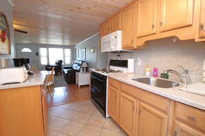 A kitchen with wooden cabinets, a microwave, a stove, and a sink.