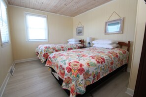 Quarto com duas camas, piso de madeira e teto inclinado.