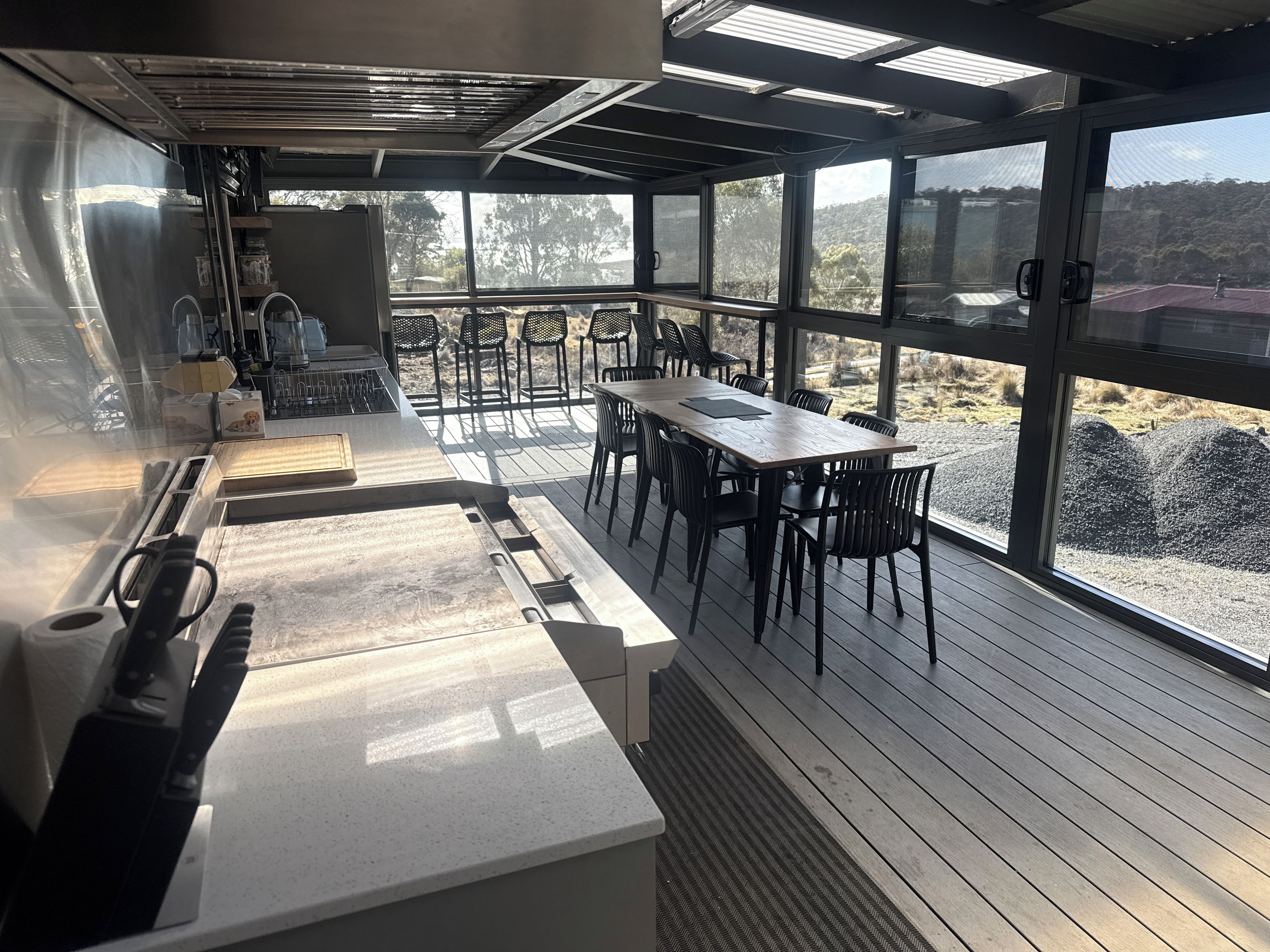 A modern kitchen with a large island, outdoor seating area with chairs, and a view of the surrounding landscape.