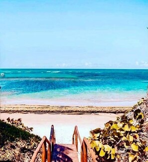 A wooden staircase leading to a beach with clear turquoise water.