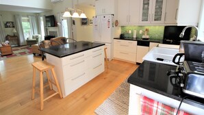 Una cocina moderna con armarios blancos, encimera negra y taburetes de madera.