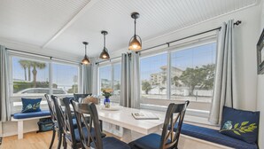 Un área de comedor con una mesa blanca, sillas oscuras y un banco con cojines.