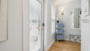 Un pasillo con paredes blancas, piso de madera y un mueble estante a rayas azul y blanco.