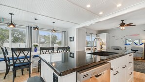 Una cocina moderna con una isla central, armarios blancos e iluminación colgante.