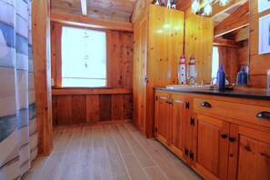 A wooden interior with a large window, a sink, and cabinets.