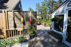 A wooden deck with outdoor furniture, a potted plant, and a hanging plant. - Lovely Post & Beam Near Indian Neck (1224) (Wellfleet)