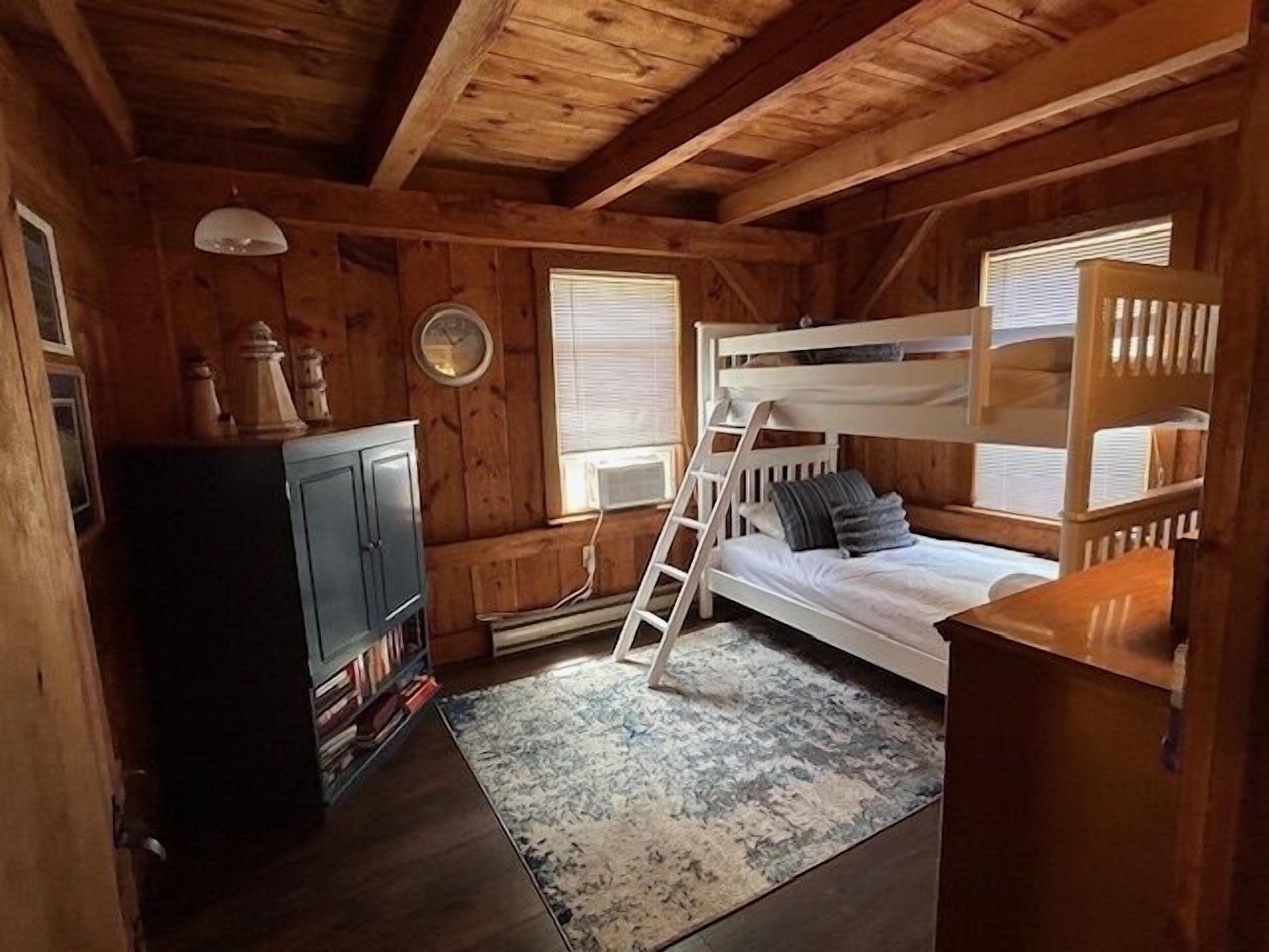 Een houten kamer met stapelbedden, een klein bureau en een boekenkast.