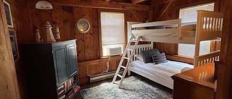 Een houten kamer met stapelbedden, een klein bureau en een boekenkast.