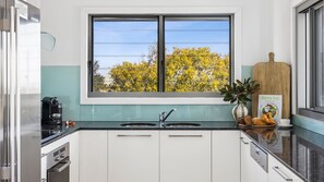 Una cocina con ventana, dos fregaderos, una cafetera y un libro de cocina en la encimera.