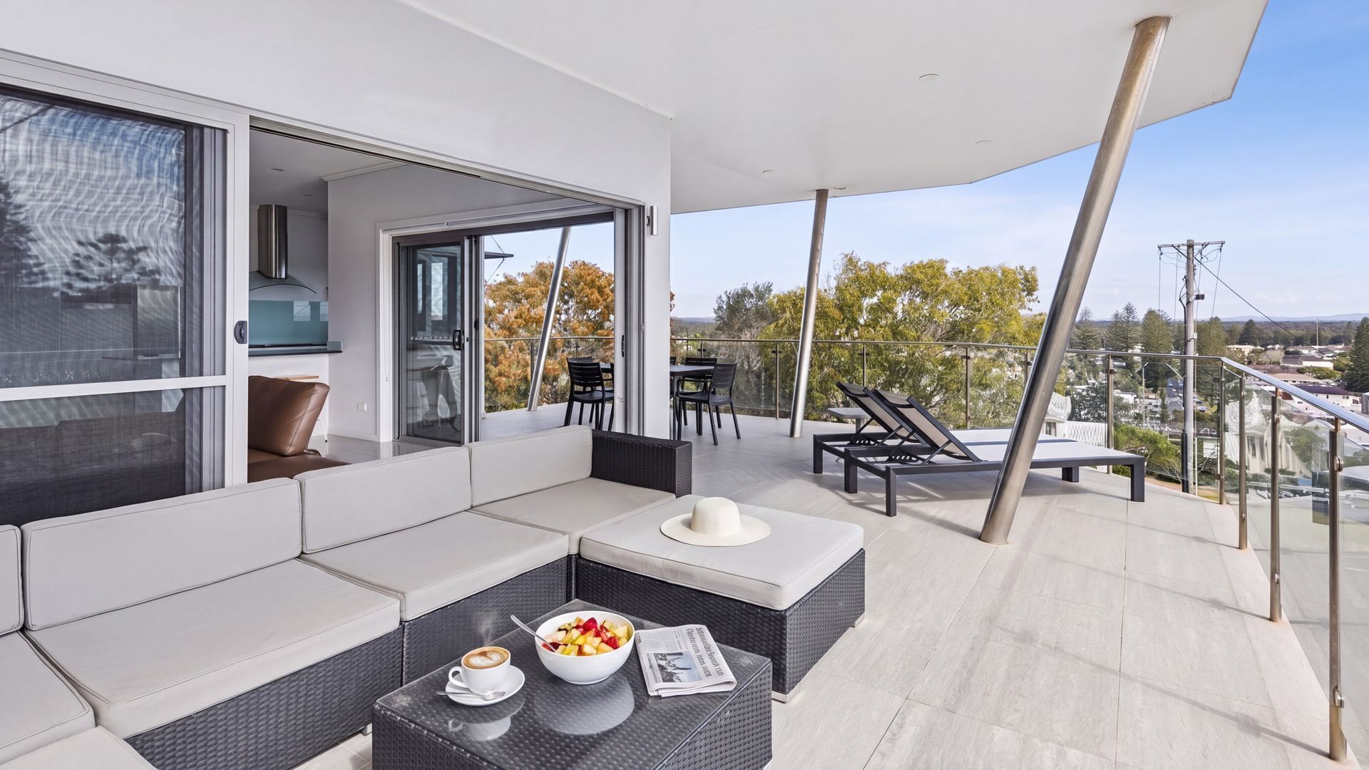 Un espace de vie extérieur moderne comprenant un canapé, une table à manger et des fauteuils de salon.
