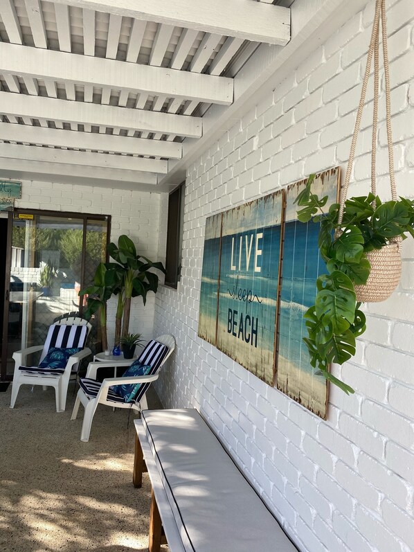 A beach-themed seating area with white brick walls, a 'LIVE BEACH' sign, and two striped chairs.