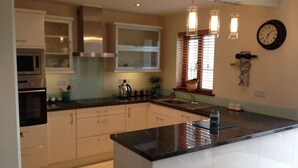 A modern kitchen with white cabinets, a black countertop, stainless steel appliances, and pendant lighting. - Cahirciveen Marina, Ring Of Kerry, 2bed/2bath House (Cahersiveen)
