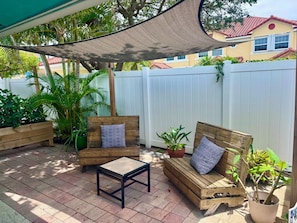 A patio with wooden furniture, a small table, and potted plants. - Two Bedroom Retreat Near Deerfield Beach Pier (Deerfield Beach)