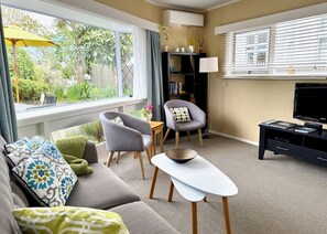 A living room with a sofa, two armchairs, a coffee table, a TV, and a bookshelf. - Riversong City Retreat - right on the edge of town (Nelson City)
