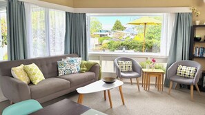 A living room with a sofa, chairs, a coffee table, and a view of the outside. - Riversong City Retreat - right on the edge of town (Nelson City)