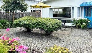 A garden with a small bush, gravel path, and a yellow umbrella. - Riversong City Retreat - right on the edge of town (Nelson City)
