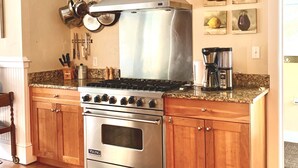 Une cuisine équipée d’une cuisinière en acier inoxydable, de meubles de rangement en bois et d’une machine à café.