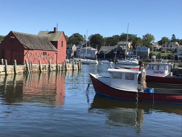 Boats moor at the dock near a charming red building with a sloping roof.