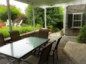 Relax on the shaded patio surrounded by lush greenery and enjoy a meal at the glass-top table.
