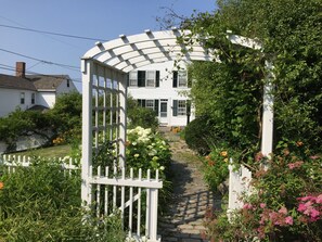 Traditional home with a shaded entrance, surrounded by a beautiful garden and a stone pathway.