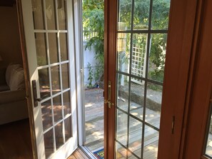 Step outside to a patio with a wooden deck and lush garden views.