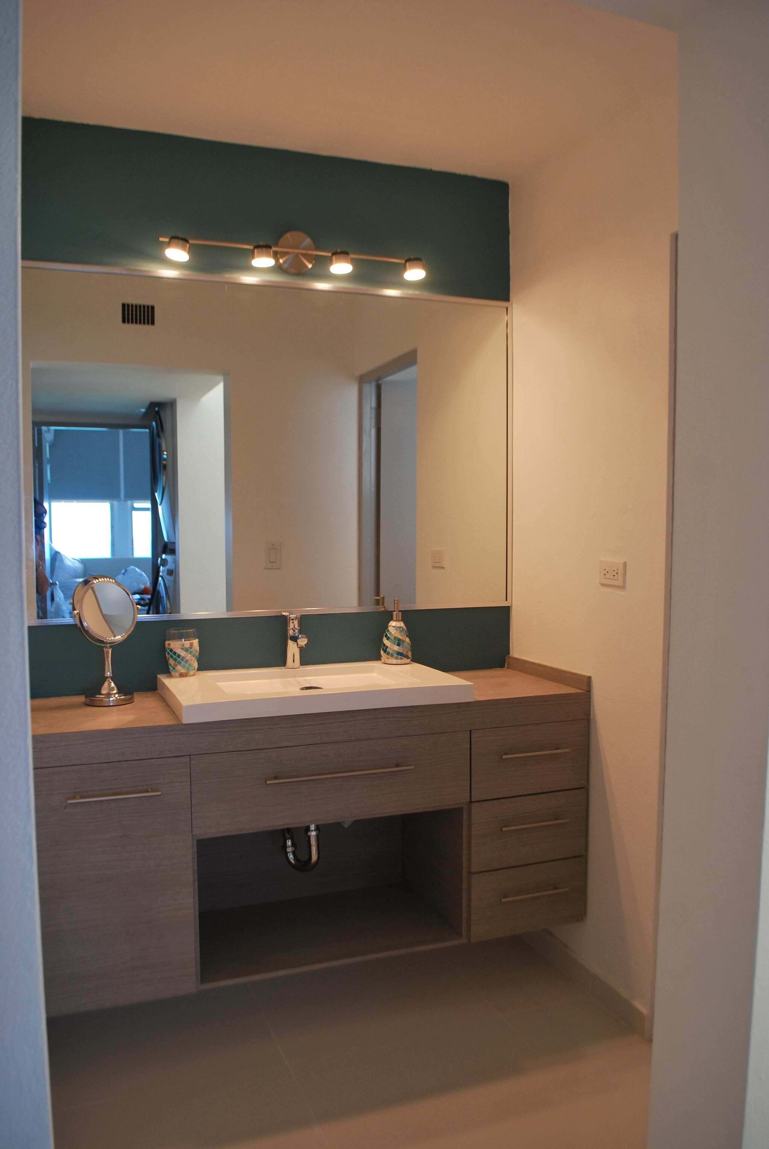 Un baño con un espejo grande, dos lavamanos y un mueble de tocador con cajones.