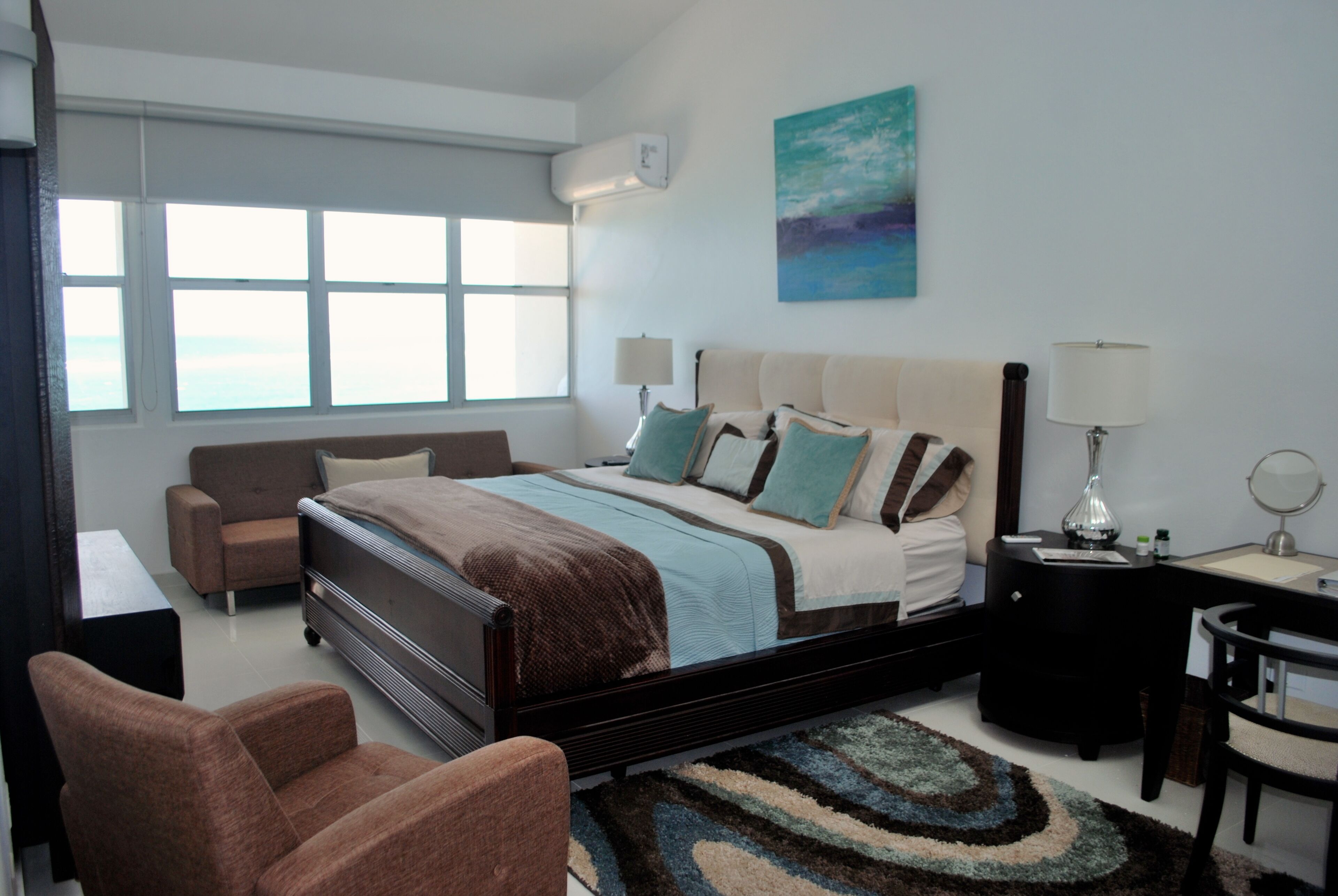 Un dormitorio moderno con una cama grande, un sofá, un escritorio y una silla.