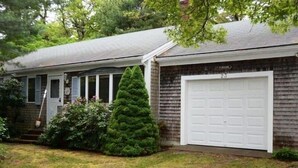 Une maison de plain-pied avec un garage, un porche à l’avant et une pelouse bien entretenue.