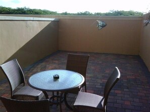 Enjoy a patio with a round table and four chairs, surrounded by a brick floor and a decorative fish emblem.