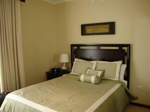 Restful retreat with a neatly made bed, bedside table, and framed artwork.