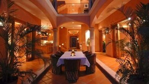 Un comedor con una mesa dispuesta para cuatro personas, rodeada de sillas, en un edificio con un ambiente cálido y un balcón con vistas al área de comedor.