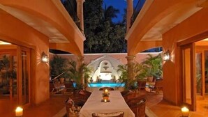 Comedor con vista a la piscina, con una mesa larga, sillas y velas.