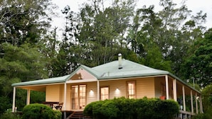A single-story house with a green roof, a covered porch, and a small front yard. - Fernridge Farm Cottage (Bellingen)