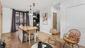 Una sala moderna con comedor, una silla de mimbre y vistas a una cocina y comedor a través de una puerta corrediza.