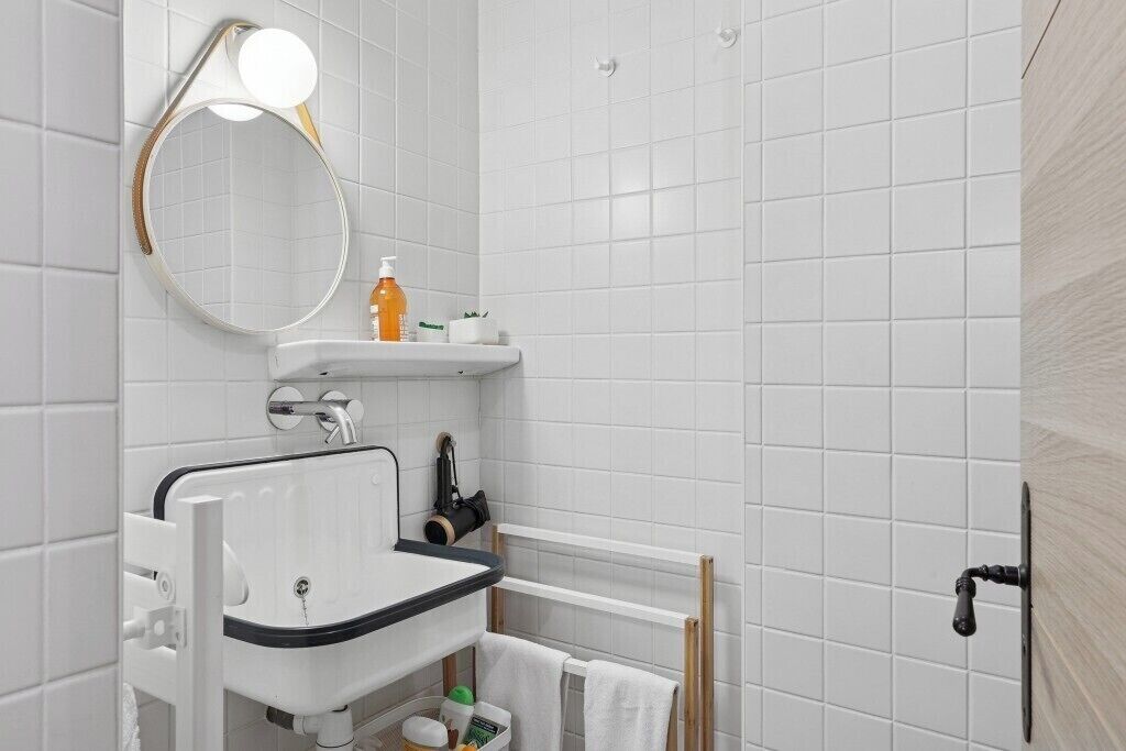 A bathroom with a white sink, mirror, and towel rack.