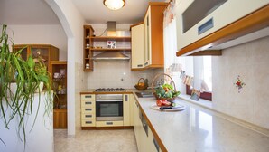 A kitchen with a stove, oven, and sink. There is a plant on the counter and a basket of fruit.